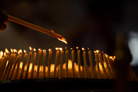 lighted candles laid out in circle in the dark with small white shadow on the right side of the...