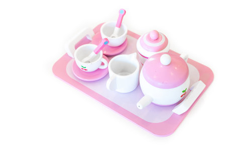 A set of pink white pastel color wood  toy tea cups including 2 coffee cups with teaspoons, a teapot, a sugar jar  and a milk jug is placed on a tray. Isolate clear on white background.の写真素材