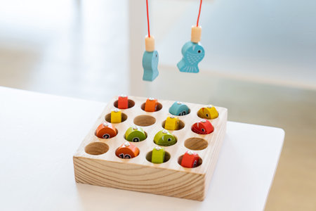 Kids are playing and finding the matched number in the wooden magnetic fishing game, using wooden fishing pole provided with magnets to attach the mouth of the fish and picking it up.の写真素材