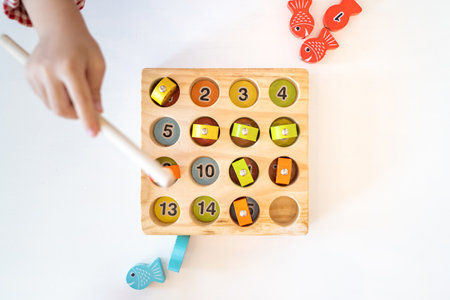 Topview, flatlay of Kid's hands are playing and finding the matched number in the wooden magnetic fishing game,の写真素材