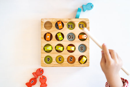 Topview, flatlay of Kid's hands are playing and finding the matched number in the wooden magnetic fishing game,の写真素材
