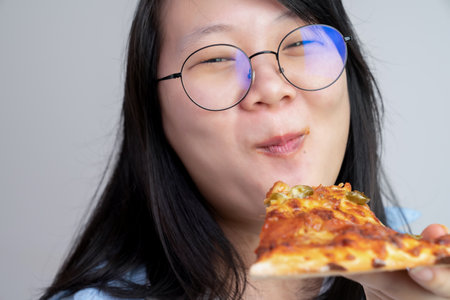 Happy glasses Asian young woman eat Pizza on white background.の写真素材