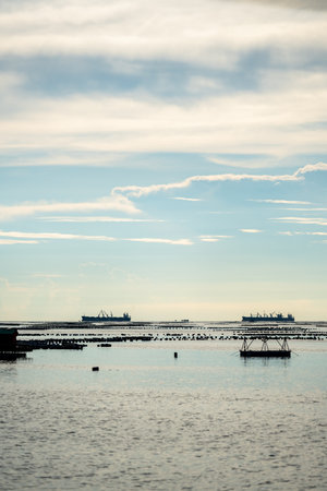 Local fishing boat and container ship are floating on the sea in clear sky day, Sriracha, Chonburi province.の写真素材
