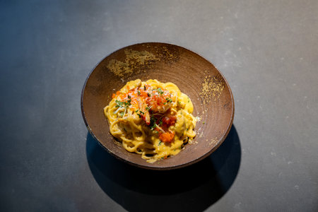 Spaghetti Carbonara pasta Egg and Cheese creamy cream sauce with Shrimp and micro herb decoration on the top of it of earthware circle bowl in studio light.の写真素材