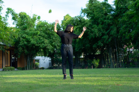 Asian short hair Woman is Joyful Jumping on the grass field garden.の写真素材