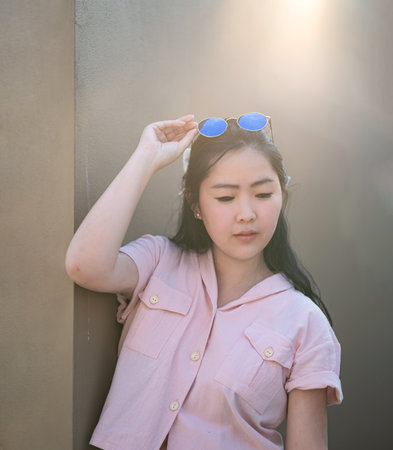 Asian glasses long hair girl is silhouette posting for camera shooting on the rooftop, top of building in twilight sunset time.の写真素材