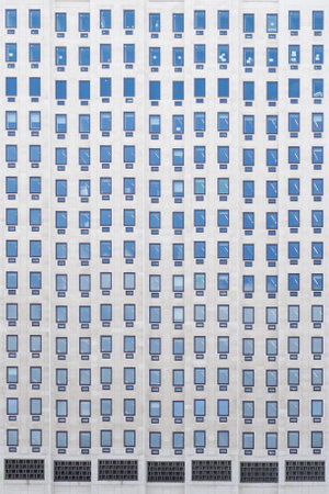 Symmetrical building facade showcases rows of blue tinted windows. Minimalist design emphasizes...
