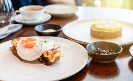 A fried sunny-side-up egg topped with black pepper sits beautifully on melted cheese toast, served...