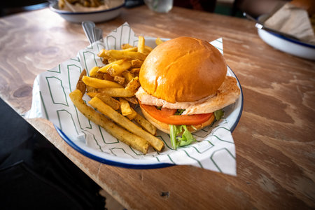 chicken burger adorned with lettuce and tomato is presented with a plentiful serving of seasoned...