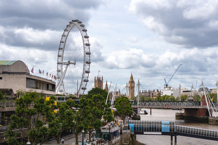 A scenic view of London highlights Big Ben and the observation wheel, blending historical and modern architecture along the riverbank.の写真素材