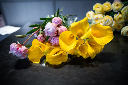 Colorful flowers in vases and bouquets are arranged neatly inside a florist shop. The natural light and variety of blooms create a fresh, elegant atmosphere.の写真素材