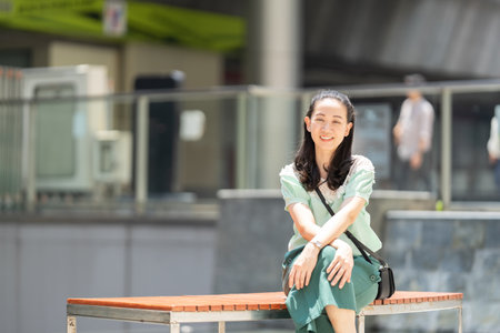 An Asian woman with long hair and green dress is sitting there pleasantly grinning.の写真素材