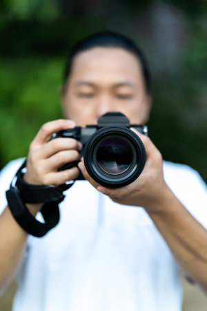 Asian man holds the Medium Format Camera in his hand and focus to shoot in front of him.の写真素材
