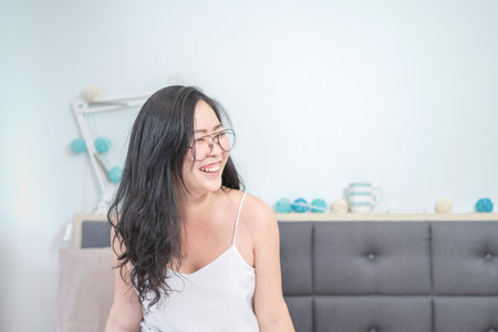 Asian Glasses Woman relax on her bed in the morning at her bedroom.