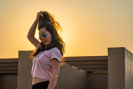 Asian glasses long hair girl is dancing on the rooftop of the building in twilight sunset time.