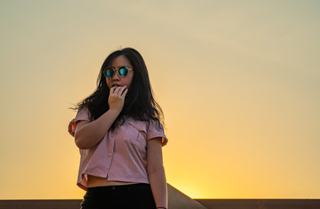 Glasses long hair girl is dancing on the rooftop of the building in twilight sunset time.の写真素材