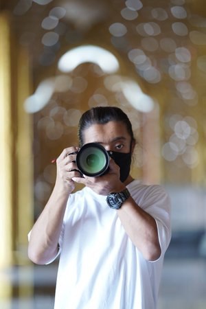 A man wearing black mask is shooting photo through a viewfinder camera.