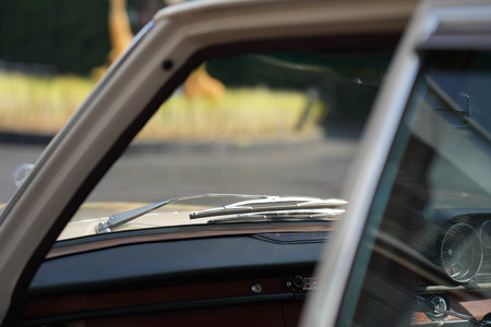 The windshield and chrome wipers of a classic car showcase the timeless allure of vintage automotive...