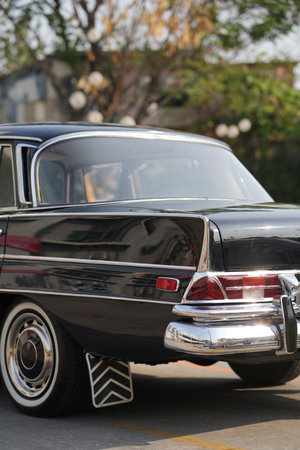 The rear wheel of a vintage black car with a classic rubber mudflap, a practical feature that blocks water and debris from affecting vehicles behind.の写真素材
