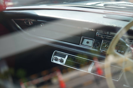 The dashboard of a vintage classic car features detailed analog gauges, a radio, and air vents in polished wood and chrome, offering a fresh yet luxurious look.の写真素材