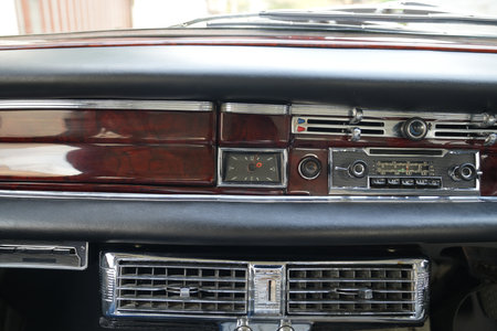The dashboard of a vintage classic car features detailed analog gauges, a radio, and air vents in...