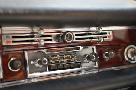The dashboard of a vintage classic car features detailed analog gauges, a radio, and air vents in polished wood and chrome, offering a fresh yet luxurious look.の写真素材