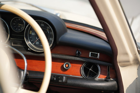 The dashboard of a vintage classic car features detailed analog gauges, a radio, and air vents in...