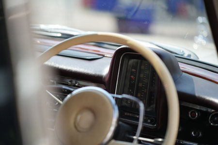 The dashboard of a vintage classic car features detailed analog gauges, a radio, and air vents in...