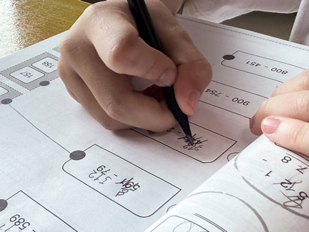 A young student sits at a wooden desk working on basic math exercises, steadily developing essential...