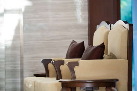 Sunlight shines on the elegant wooden sofa upholstered with ivory velvet fabric and a round coffee table set in a living room.の写真素材