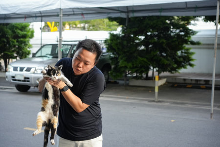 Gentle Encounter, a man carefully lifts a cat in his arms sharing a quiet moment of trust tenderness and connection between human and animal.の写真素材
