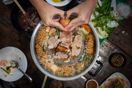Sliced meat and vegetables cook in a metal grill pot filled with broth and steam, while the center grill browns the meat.の写真素材