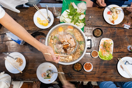 Sliced meat and vegetables cook in a metal grill pot filled with broth and steam, while the center grill browns the meat.の写真素材