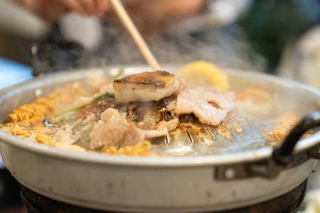 Sliced meat and vegetables cook in a metal grill pot filled with broth and steam, while the center grill browns the meat.の写真素材