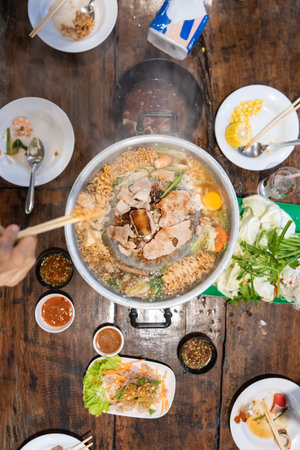 Sliced meat and vegetables cook in a metal grill pot filled with broth and steam, while the center grill browns the meat.の写真素材