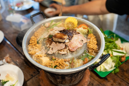 Sliced meat and vegetables cook in a metal grill pot filled with broth and steam, while the center grill browns the meat.の写真素材