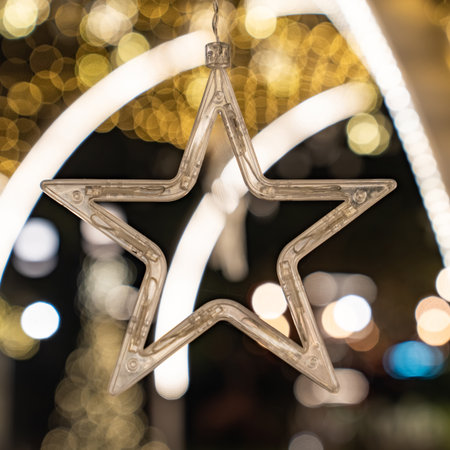 A star shaped clear light appears against warm golden bokeh, and the glowing circles form a gentle festive mood.の写真素材
