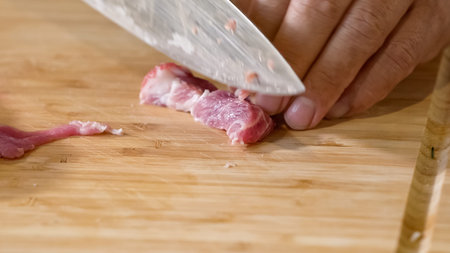 Close up of chef Butcher cutting pork meat with knife on kitchen, cooking food. The chef butcher preparing pork meat for cooking.の写真素材