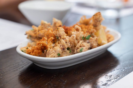 Crispy fried squid tentacles served on a plate with a lemon wedge in a restaurant setting, a golden...
