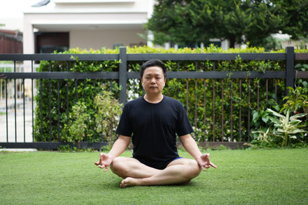 Seated in Easy Pose with gentle breath, cultivates calm steady awareness in quiet garden. Eyes closed, spine tall, the moment centers mind, body for simple daily mindfulness ritual.の写真素材