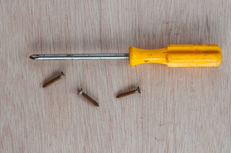 screwdriver and three screws on wood backgroundの写真素材