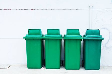old green plastic trash on white cement wall backgroundの写真素材