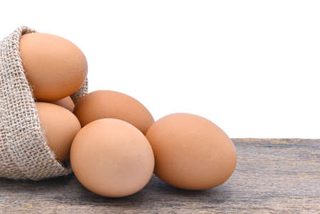 chicken eggs in burlap sack on old wood and white background close upの写真素材