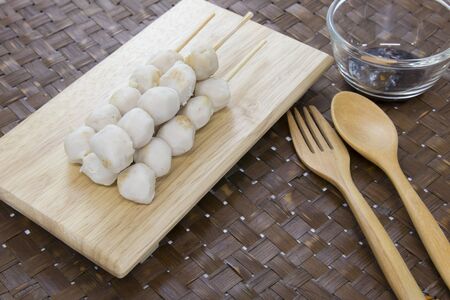 Grilled meatball on skewers served in the wooden plate with sauce.の写真素材