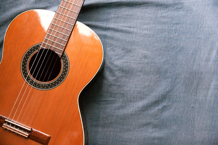 Acoustic guitar resting against a fabric background with copy spaceの写真素材