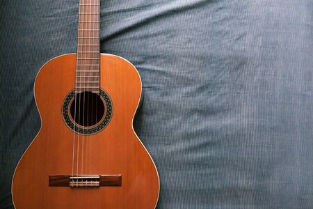 Acoustic guitar resting against a fabric background with copy space