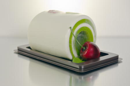 Fancy soap in roll cake form with cherry on steel boardの写真素材
