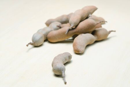 Tamarind or bitter gourd (Also called as Cucurbitaceae, bitter gourd, balsam apple, balsam pear, bitter cucumber, bitter melon, tamarind gourd) isolated on wood backgroundの写真素材