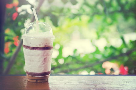 Cold coffee cup on the wooden table with bokeh background in coffee shop filter applyの写真素材