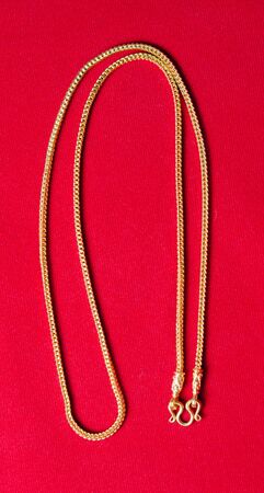 Gold necklace 96.5 precent Thai gold grade with gold hook isolated on red backgroundの写真素材